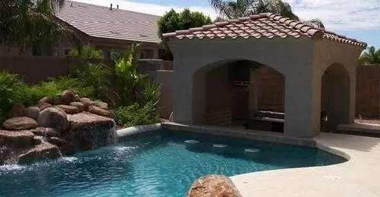 Professional pool renovation in Chandler featuring a sunken bar and rock waterfall
